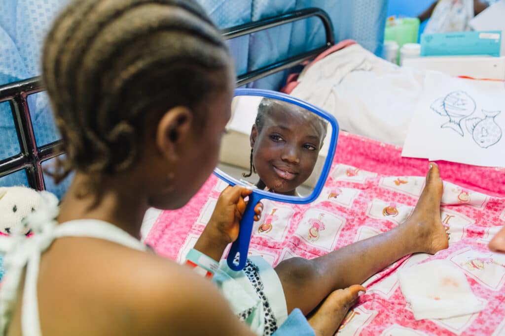 Houssainatou après l'opération de sa tumeur au visage sur l'Africa Mercy, se regardant dans le miroir