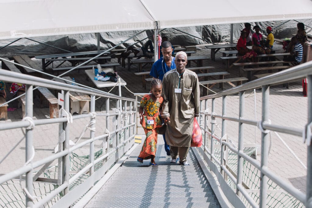 Houssainatou et son père Souleyman montant sur l'Africa Mercy pour l'opération de la tumeur au visage de la petite fille
