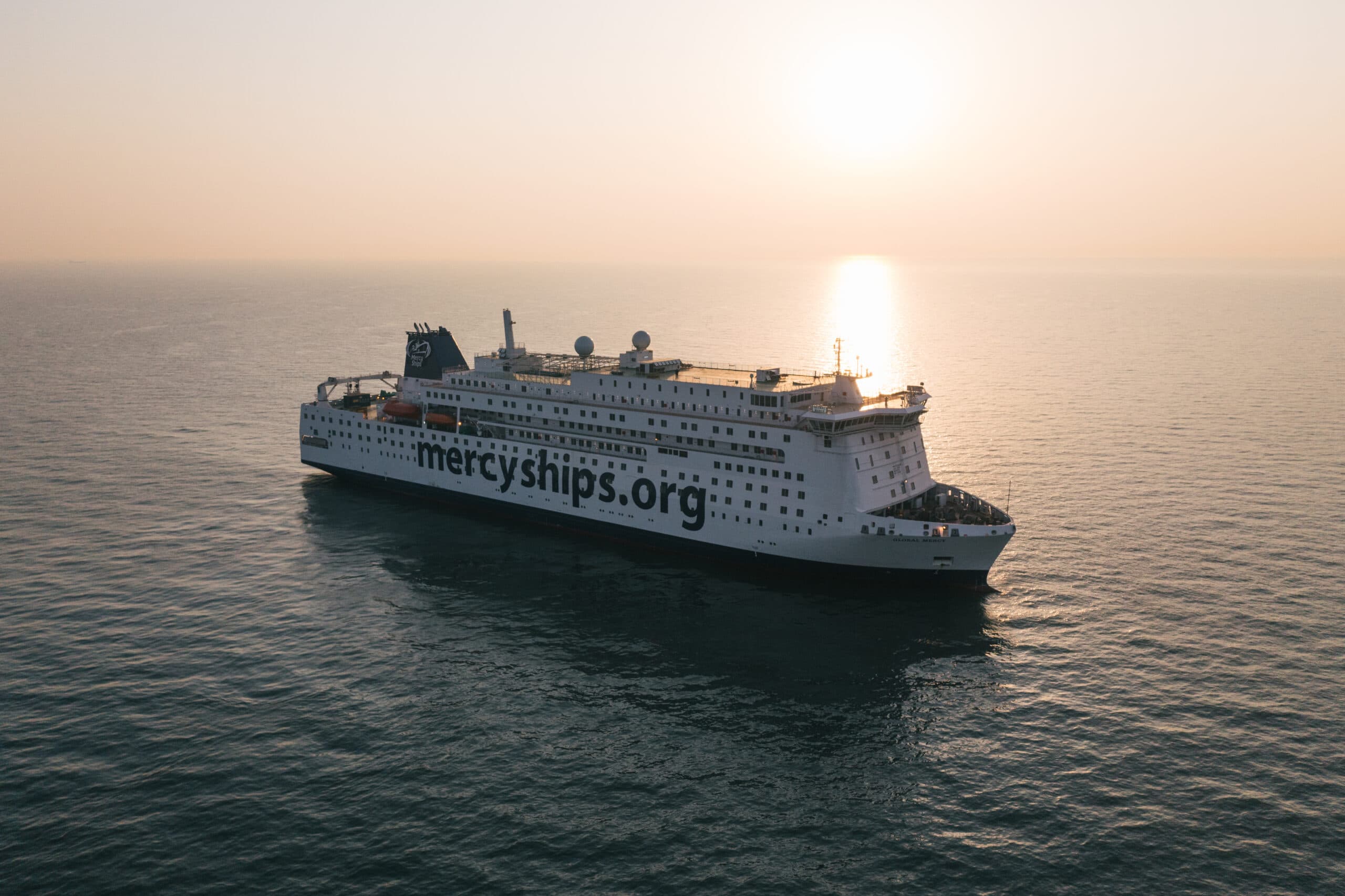 Photo du navire-hôpital Global Mercy naviguant en mer, couché de soleil